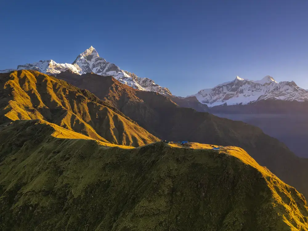 Golden dawn light on snow-covered Himalayan peaks under a vast calm sky